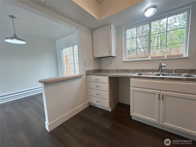 kitchen with baseboards, a sink, dark wood-style flooring, and white cabinets