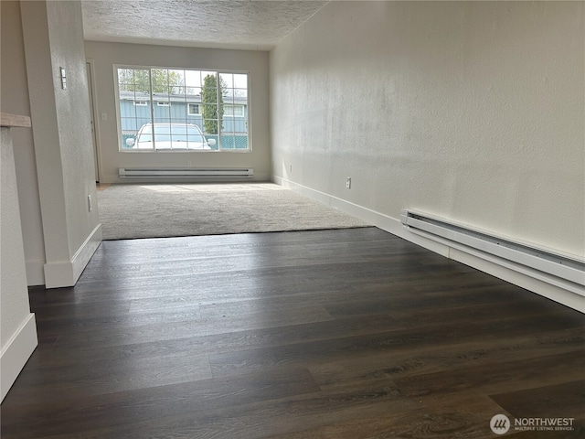 unfurnished room with a textured ceiling, baseboards, a baseboard heating unit, and wood finished floors