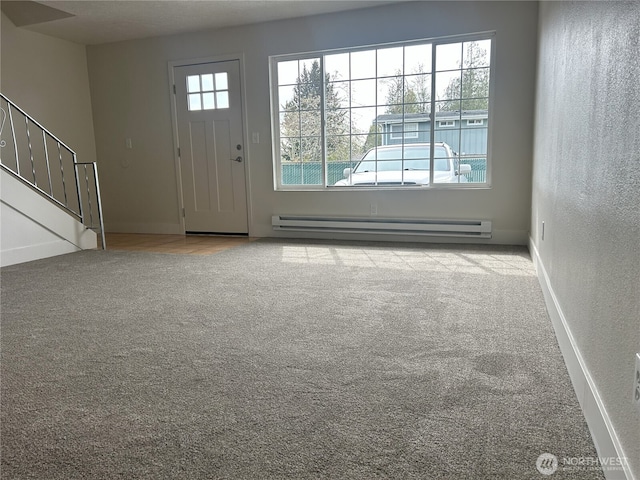 carpeted entrance foyer with stairs, baseboards, and a baseboard heating unit