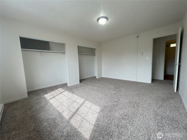 unfurnished bedroom with baseboards, two closets, and carpet flooring