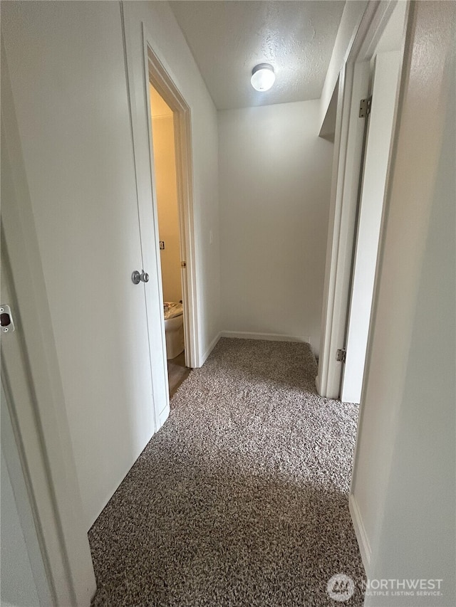 corridor with a textured ceiling and baseboards