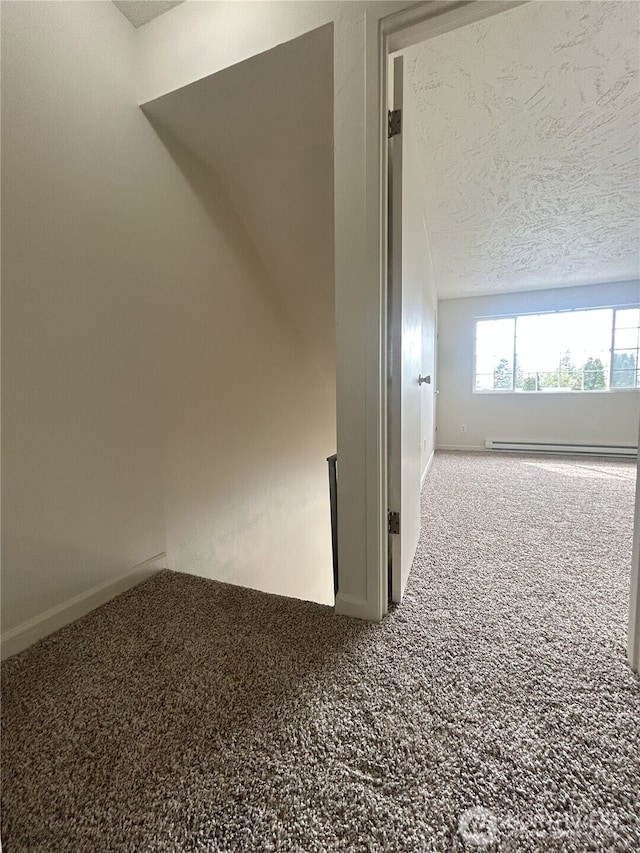 spare room with a textured ceiling, baseboards, and carpet