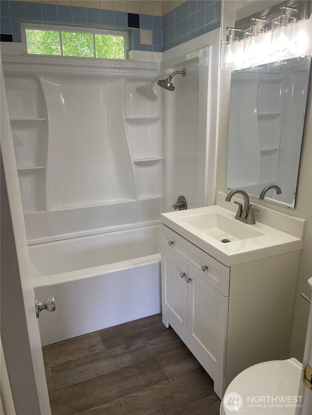 bathroom featuring vanity, toilet, wood finished floors, and shower / washtub combination