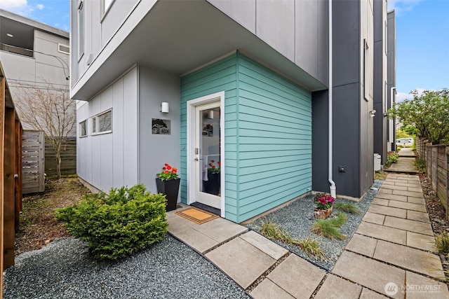 property entrance with board and batten siding and fence