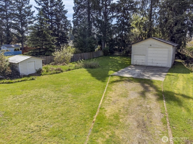 view of yard featuring an outbuilding, a detached garage, and fence