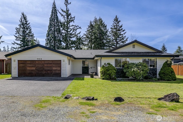 ranch-style home with a garage, fence, aphalt driveway, and a front lawn