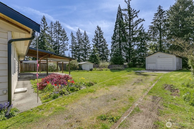view of yard with an outbuilding, driveway, a garage, and fence