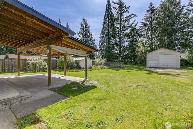 view of yard with a patio, fence, an outdoor structure, and a detached garage