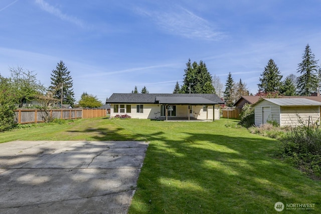 back of property featuring a lawn, fence, an outdoor structure, and a storage shed