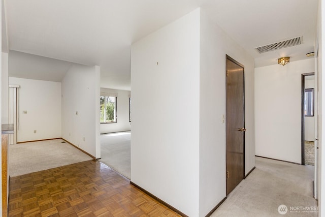 corridor featuring visible vents, light carpet, and baseboards