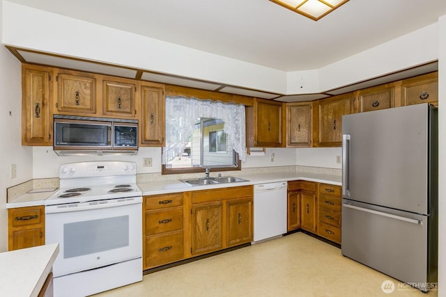 kitchen with a sink, brown cabinets, and white appliances