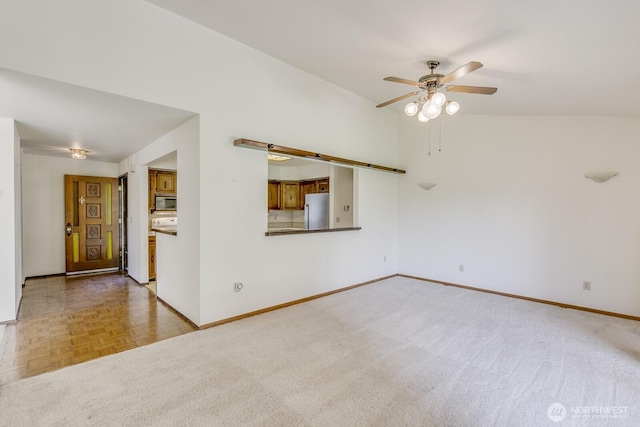 carpeted empty room featuring baseboards, a ceiling fan, and lofted ceiling