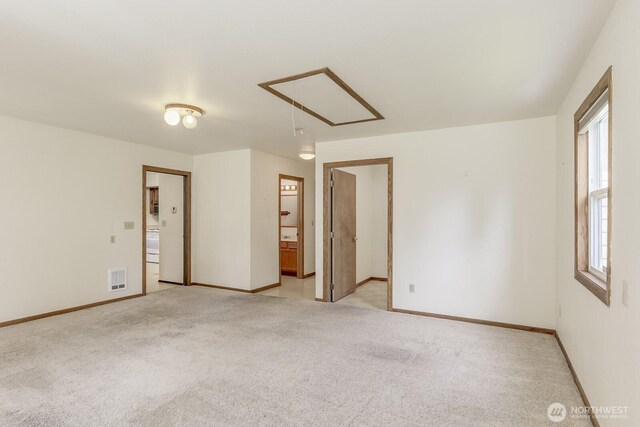 unfurnished room featuring baseboards, visible vents, attic access, and light colored carpet