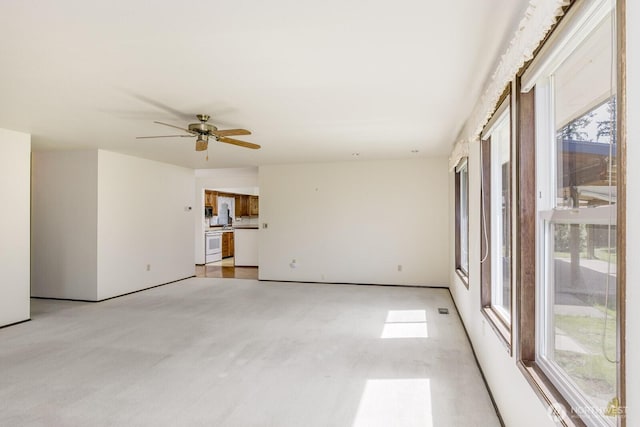 unfurnished living room featuring light carpet, a healthy amount of sunlight, and ceiling fan