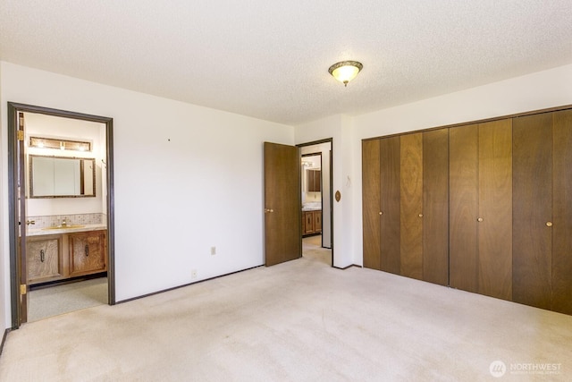 unfurnished bedroom featuring connected bathroom, a closet, a sink, and light colored carpet