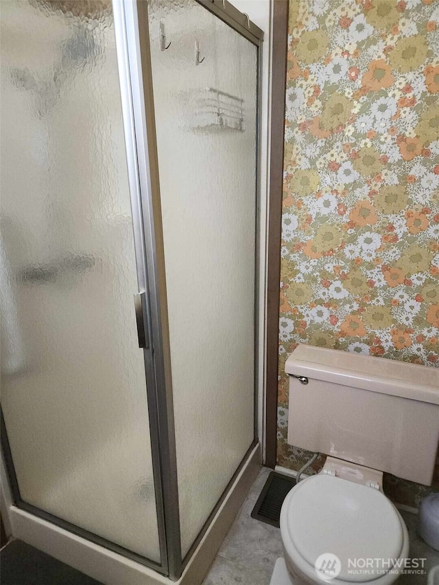 bathroom featuring toilet, a stall shower, and wallpapered walls