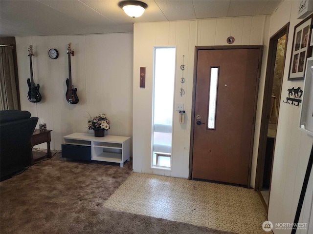 foyer with elevator, carpet floors, and a decorative wall