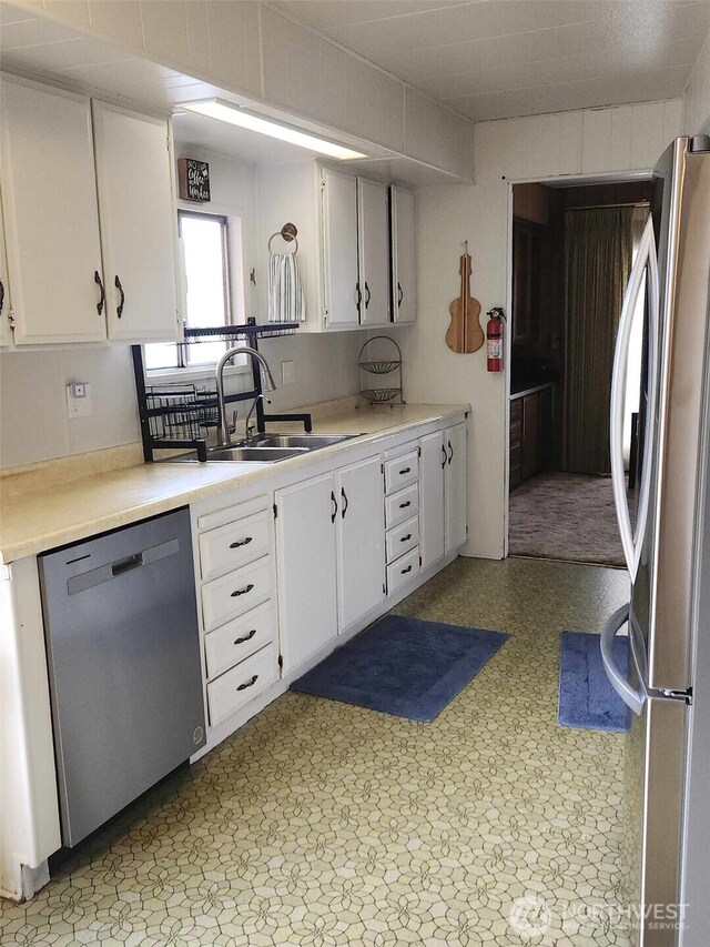 kitchen with light countertops, white cabinetry, a sink, and appliances with stainless steel finishes
