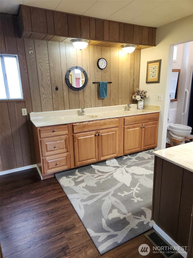 full bath featuring wooden walls, vanity, and wood finished floors