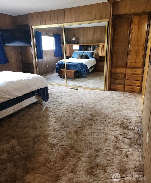carpeted bedroom featuring wooden walls