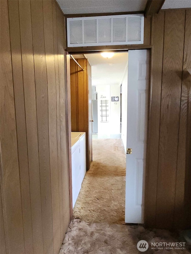 corridor with light carpet, wooden walls, and visible vents