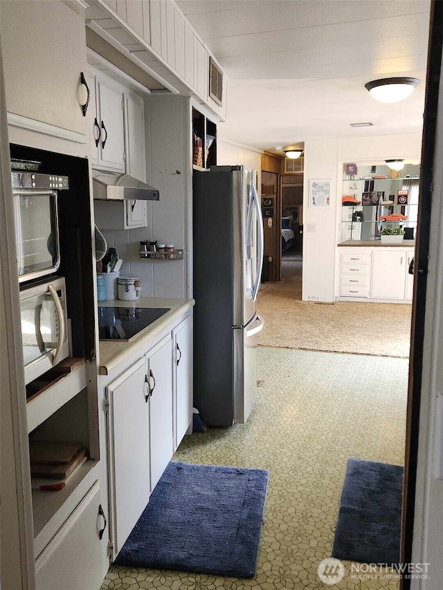 kitchen featuring stainless steel fridge with ice dispenser, visible vents, white cabinets, and black electric cooktop