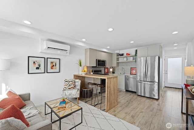 living area featuring recessed lighting, light wood-style floors, and a wall unit AC