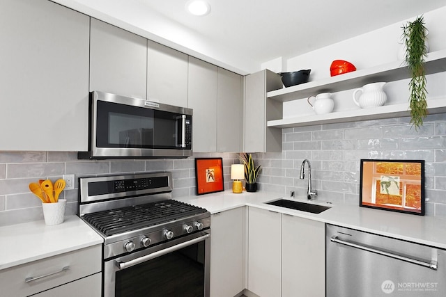 kitchen featuring stainless steel appliances, a sink, decorative backsplash, open shelves, and light countertops