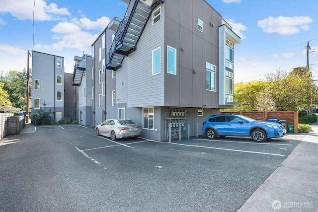 view of building exterior featuring uncovered parking and fence
