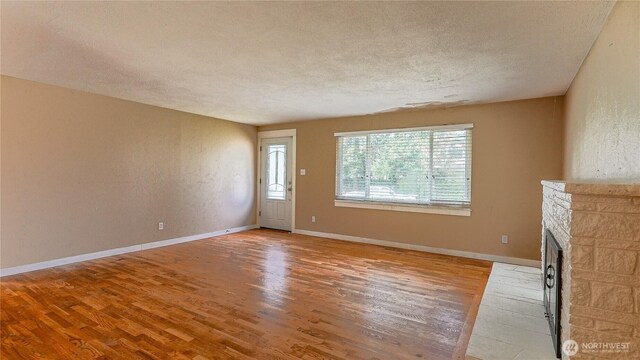 2125 N Highland St, Tacoma, WA 98406 - unfurnished living room with a textured wall, a fireplace, a textured ceiling, and wood finished floors