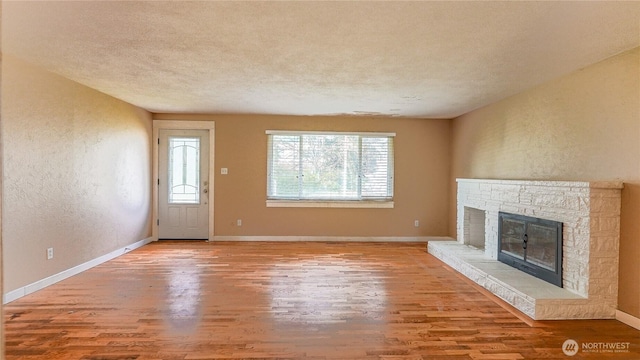 2125 N Highland St, Tacoma, WA 98406 - unfurnished living room with wood finished floors, a textured wall, baseboards, and a stone fireplace