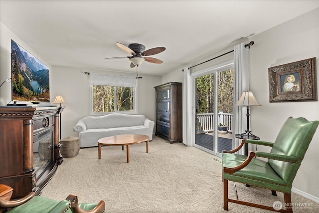 carpeted living area featuring plenty of natural light, a ceiling fan, and baseboards