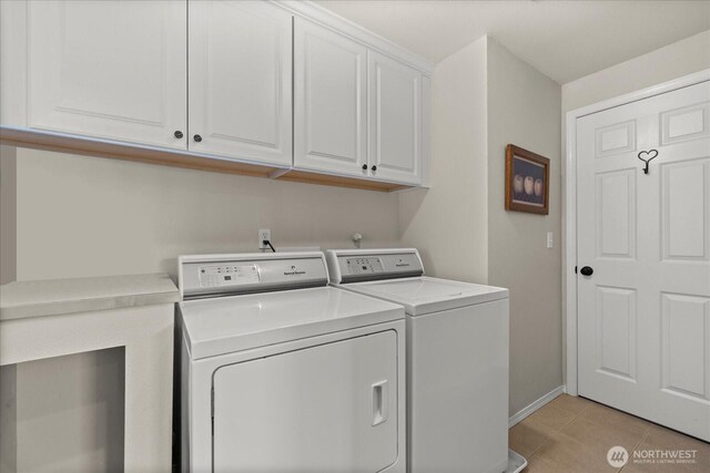 laundry room featuring baseboards, cabinet space, washer and clothes dryer, and light tile patterned floors