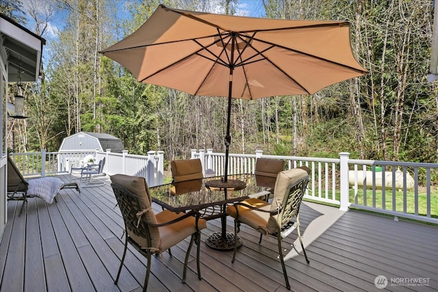 deck featuring an outdoor structure, a storage unit, and outdoor dining space
