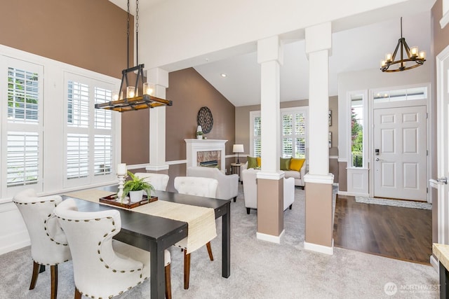 1231 148th Pl SE, Mill Creek, WA 98012 - carpeted dining space with a chandelier, decorative columns, a fireplace, high vaulted ceiling, and baseboards