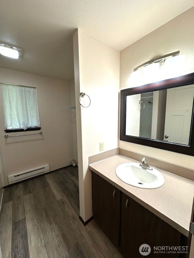 bathroom with a baseboard heating unit, wood finished floors, and vanity