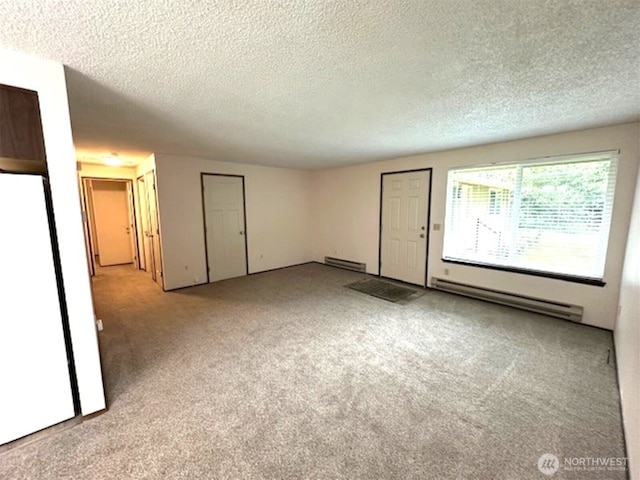 carpeted spare room with a textured ceiling and baseboard heating