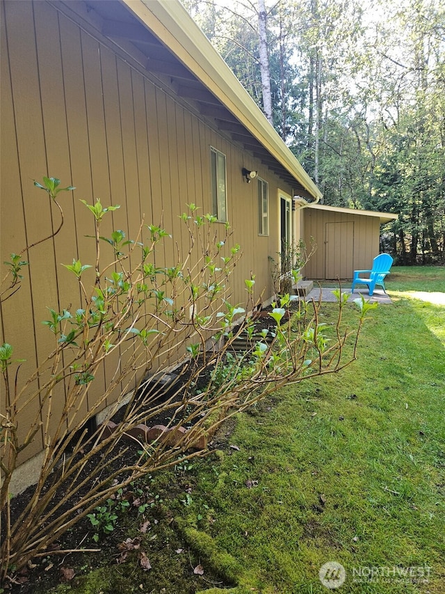 view of side of property with a storage unit, an outdoor structure, and a yard
