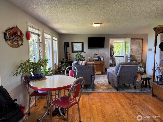 4751 State Route 109, Moclips, WA 98562 - dining area with light wood finished floors, a textured ceiling, and a wood stove