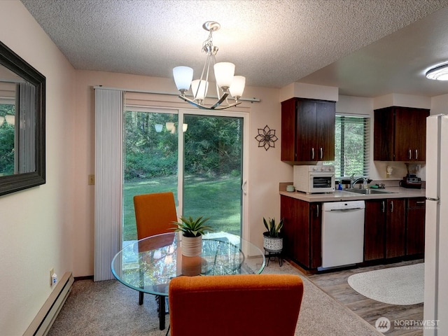 kitchen featuring a sink, white appliances, light countertops, a chandelier, and a baseboard radiator