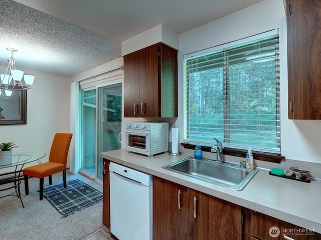kitchen with a wealth of natural light, light countertops, a sink, dishwasher, and a notable chandelier