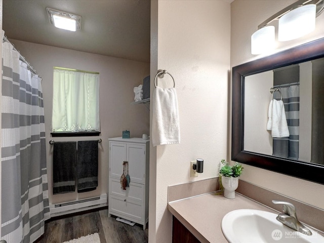 bathroom with a baseboard heating unit, wood finished floors, and vanity