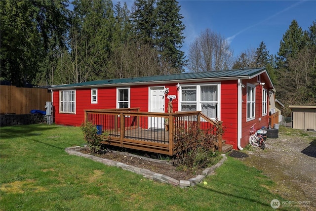 view of front of house with a front lawn, fence, a deck, and metal roof
