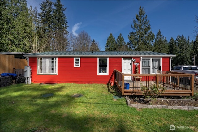 view of front of home featuring metal roof, a front yard, and a deck