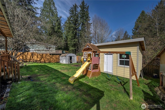view of yard featuring an outbuilding, a shed, a fenced backyard, and a playground