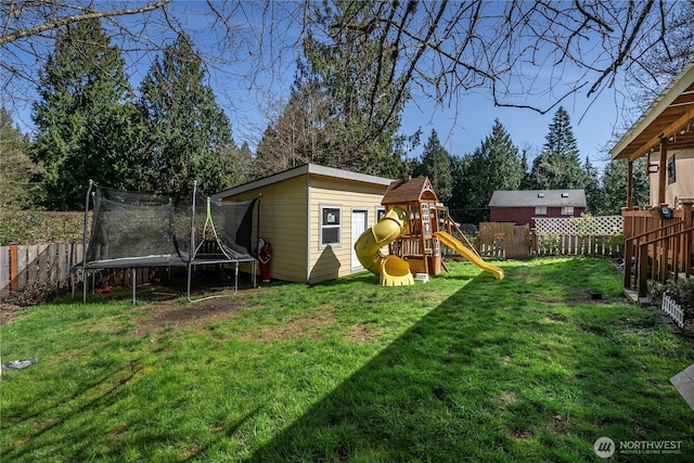 view of yard featuring a trampoline, a fenced backyard, and a playground
