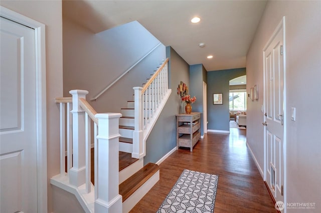 foyer featuring wood finished floors, recessed lighting, stairs, baseboards, and arched walkways
