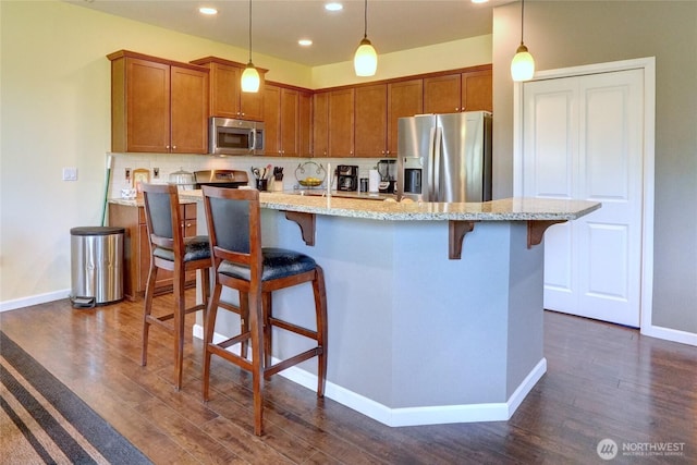 kitchen with stainless steel appliances, dark wood-style floors, baseboards, tasteful backsplash, and brown cabinetry