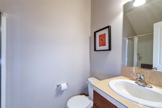 bathroom featuring a shower stall, toilet, vanity, and vaulted ceiling