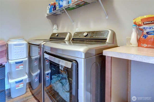 clothes washing area with washer and clothes dryer and wood finished floors